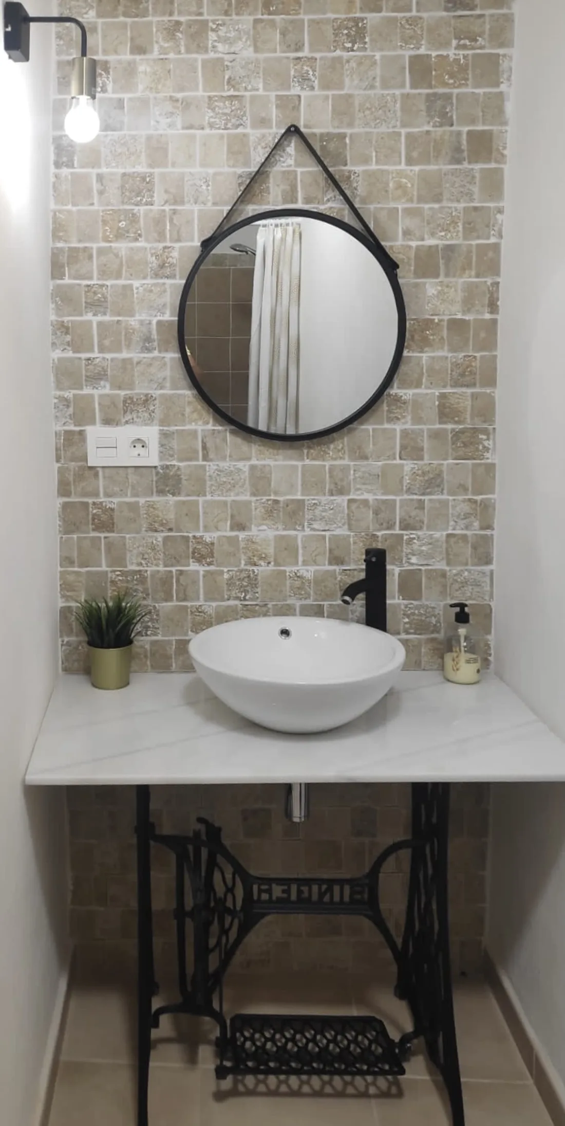Baño con lavabo sobre encimera y espejo redondo