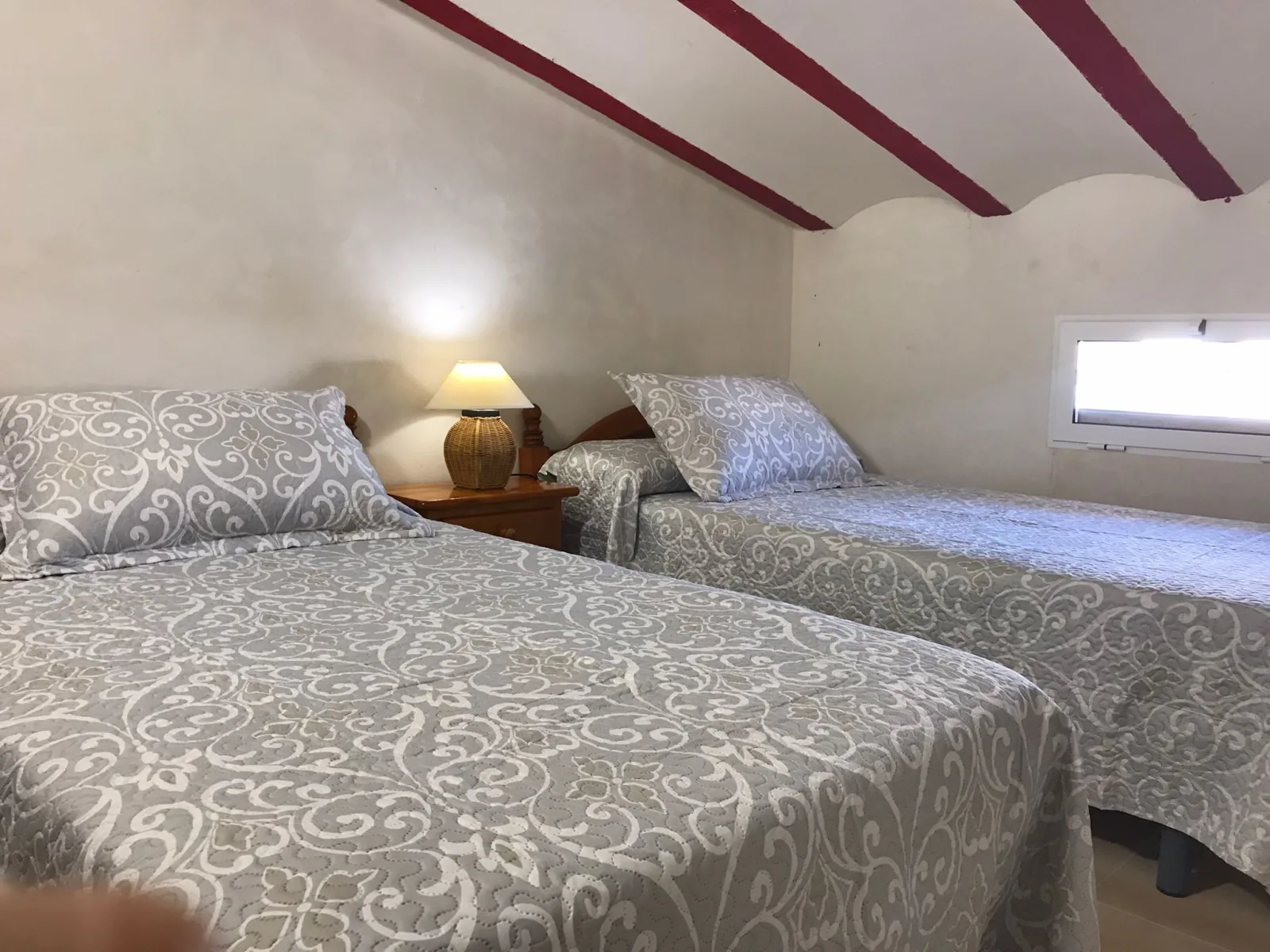 Dormitorio abuhardillado bajo vigas de madera